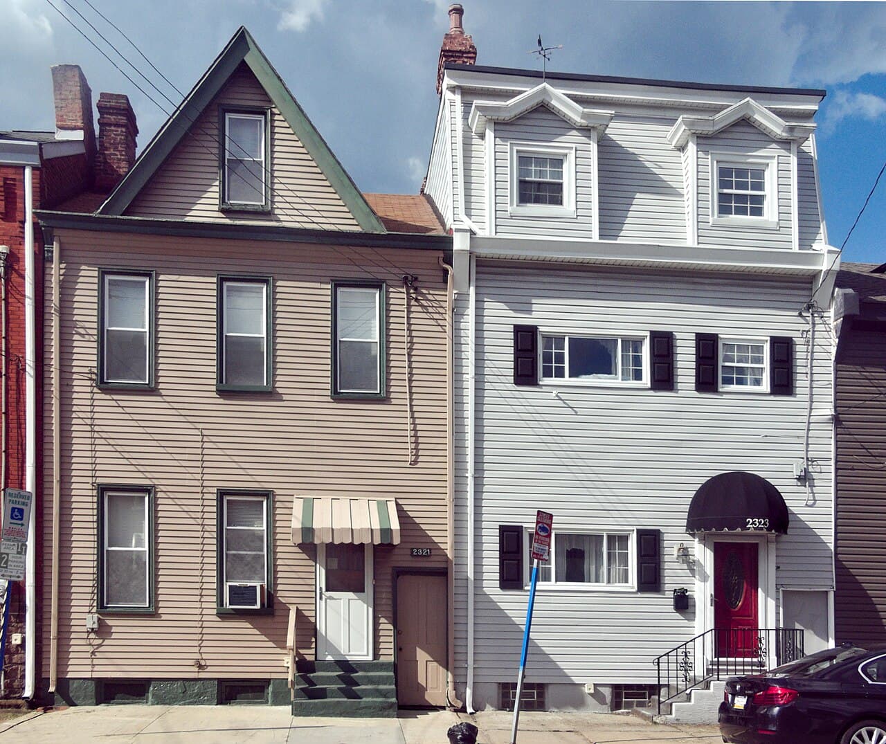 Two neighboring row houses with vinyl siding, one beige and one light gray