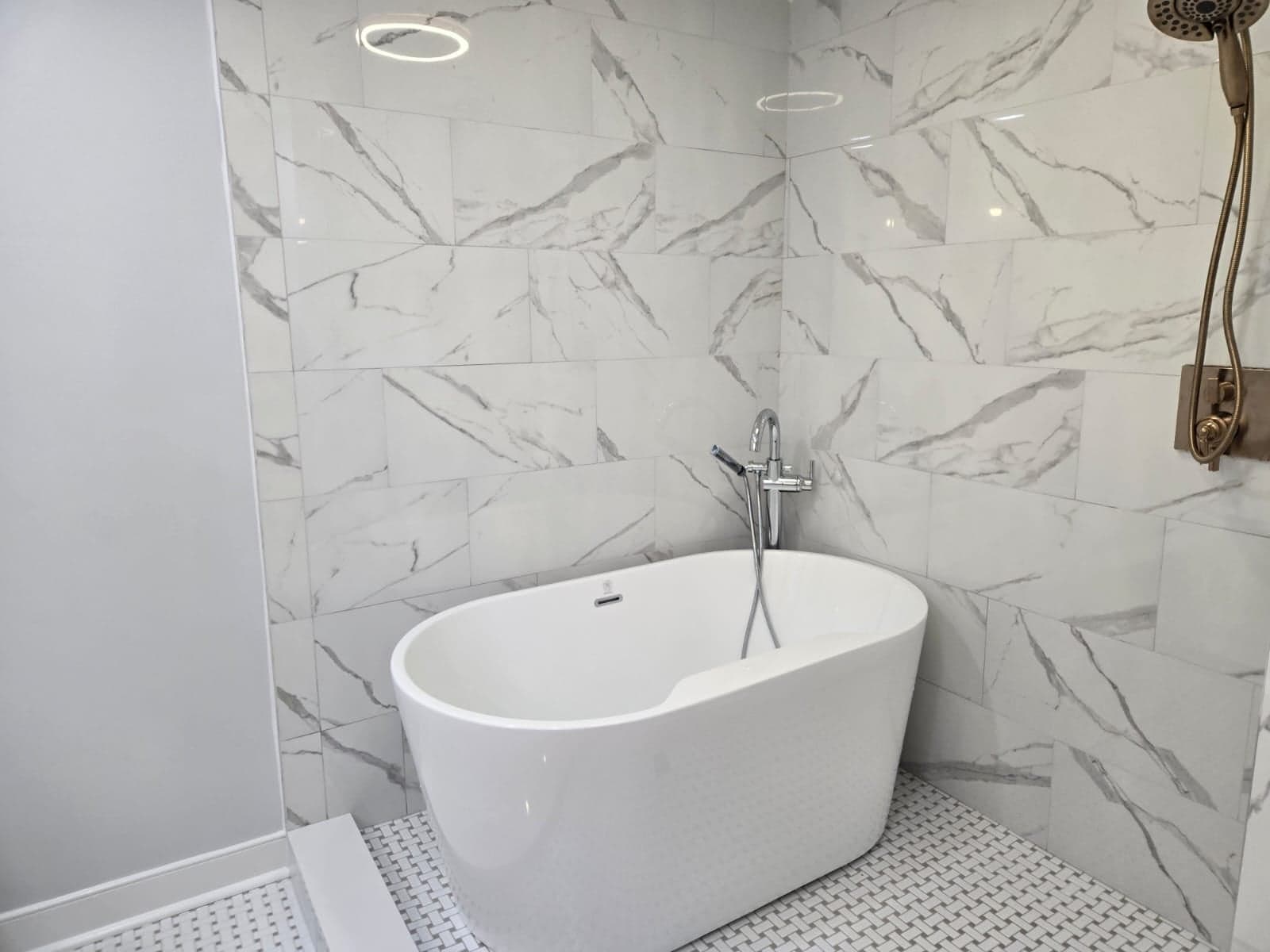 Bathroom remodel in Richmond, VA by MAS Contractors — freestanding tub with large-format marble-veined tile and basketweave mosaic floor